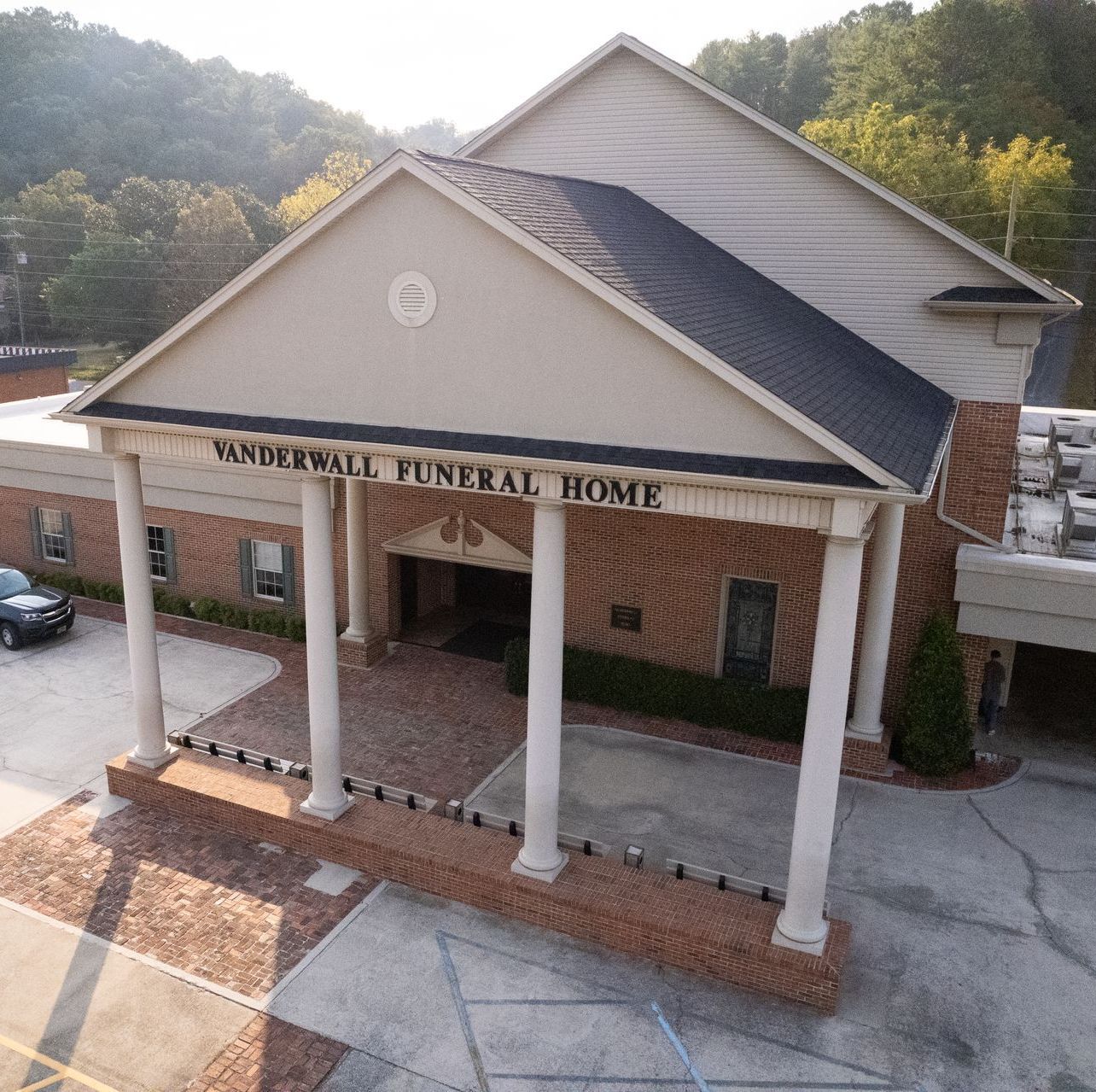 A wooden walkway leading to a gazebo overlooking a body of water at sunset.
