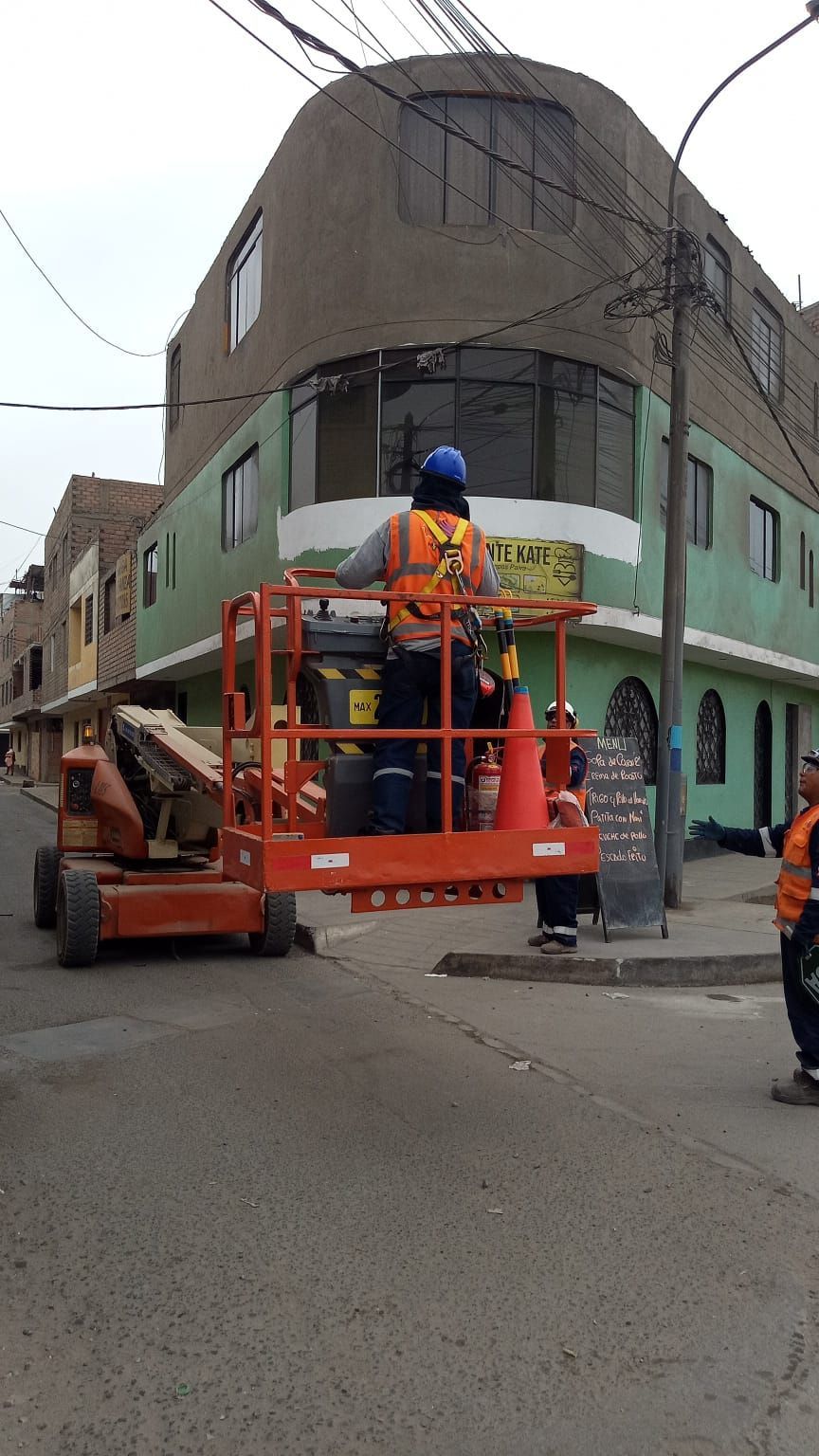 Un trabajador, subido a una plataforma elevadora, repara la esquina de un edificio en una calle de la ciudad.