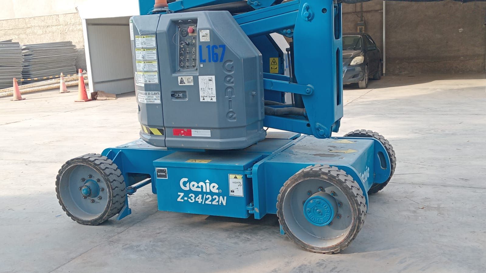 Plataforma elevadora de tijera Blue Genie estacionada sobre concreto en un estacionamiento al aire libre.