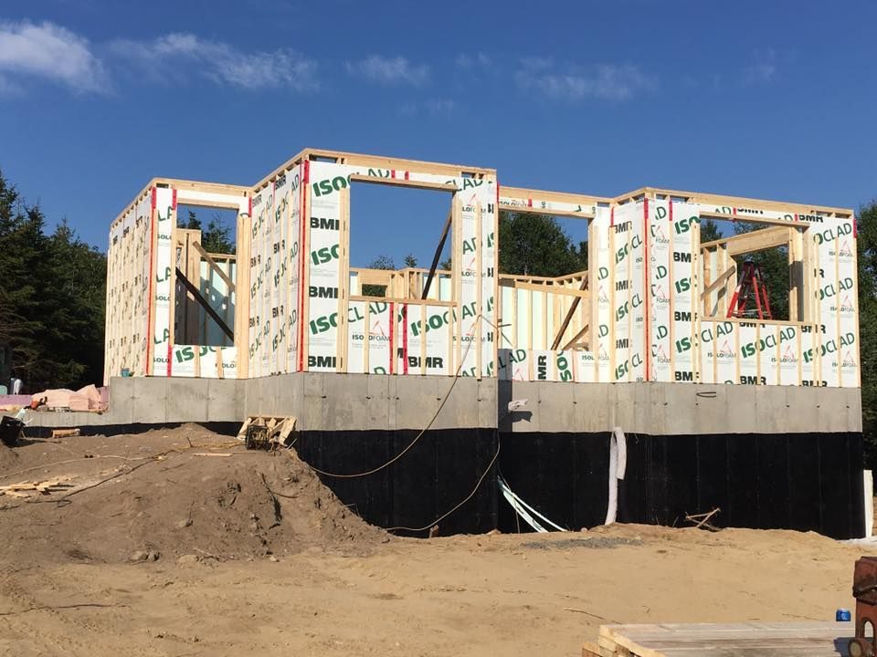 Une maison est en construction au milieu d'un champ de terre.
