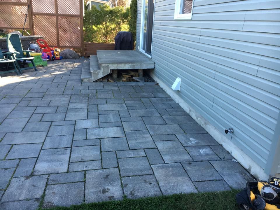 Un patio avec une tondeuse à gazon devant une maison.