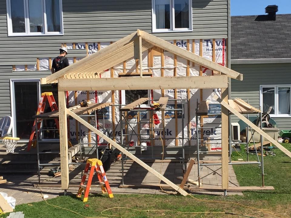 Une structure en bois est en cours de construction devant une maison.