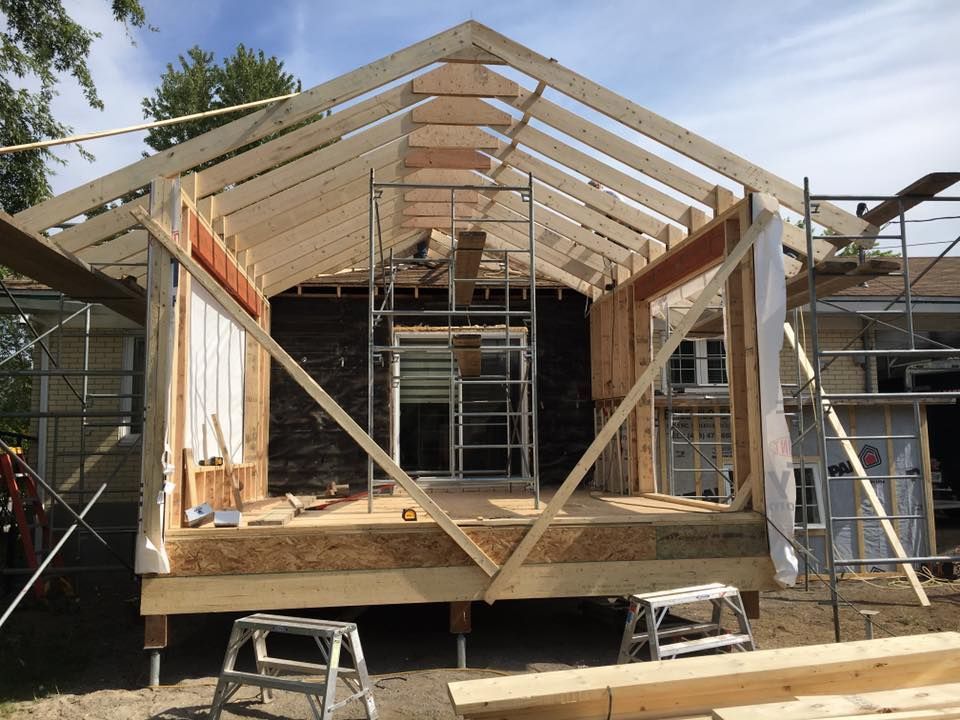 Une maison est en cours de construction avec des poutres en bois et des échafaudages.