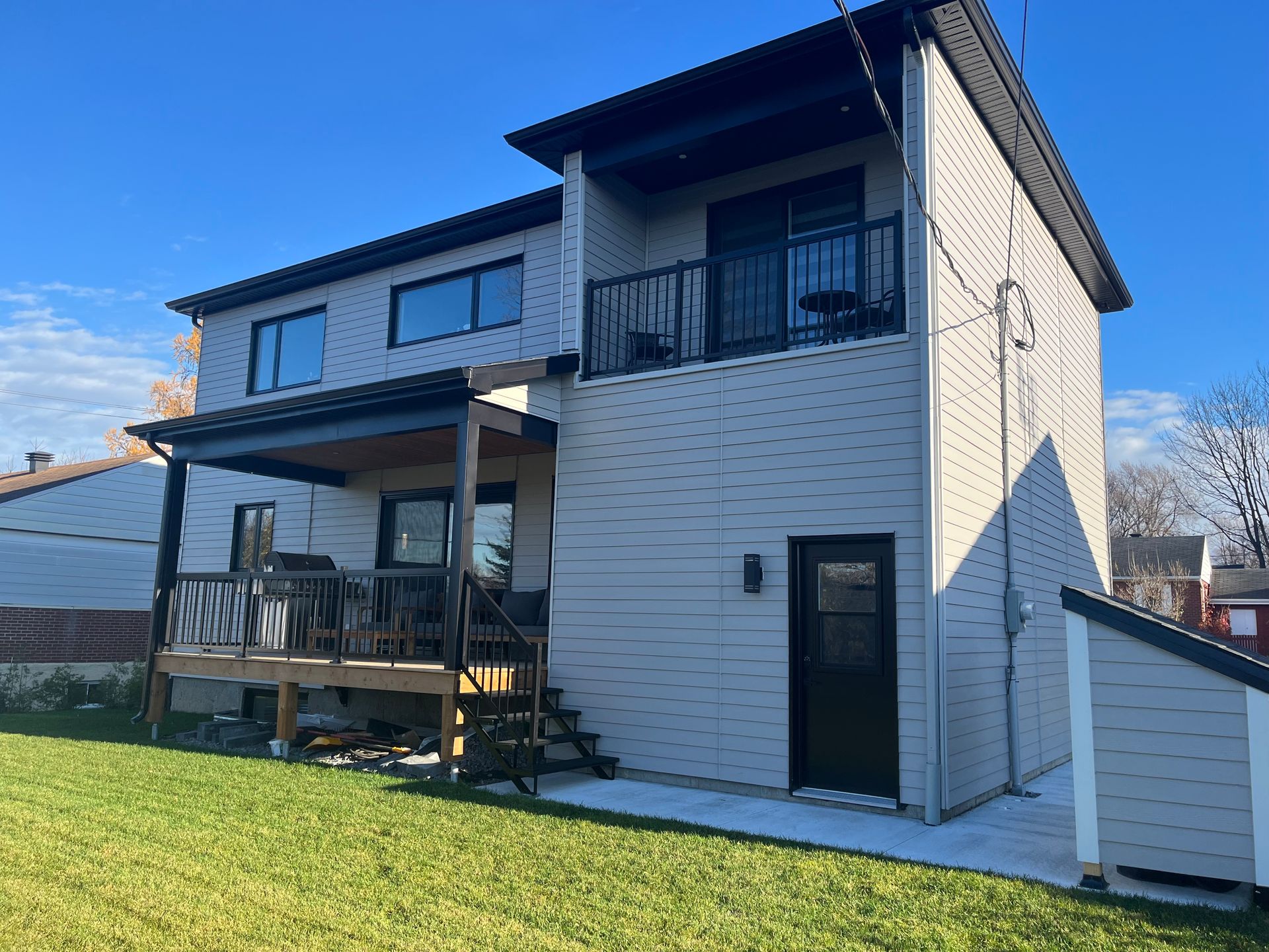 Une maison blanche avec une terrasse et des escaliers dans l'arrière-cour.