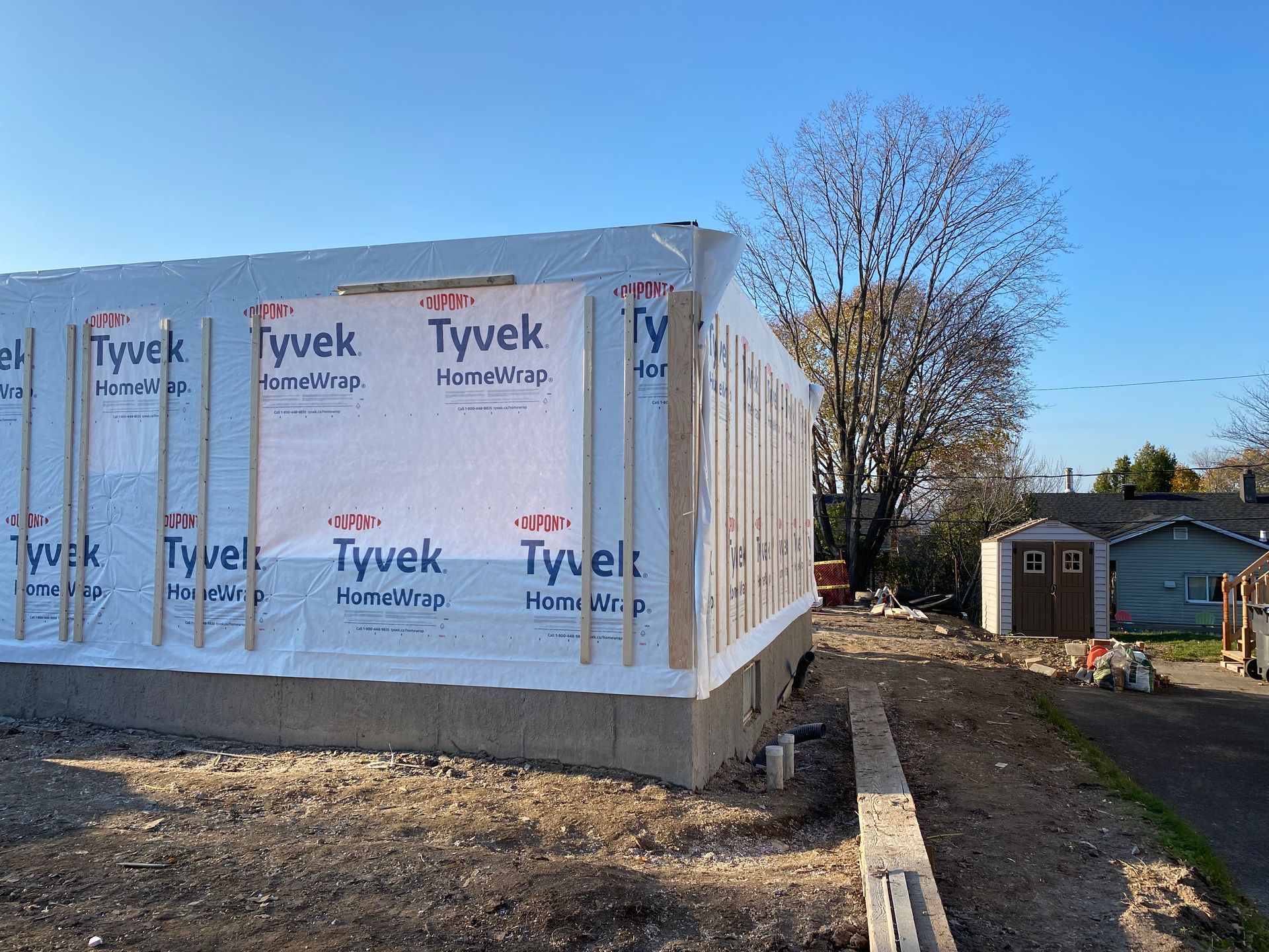 Un bâtiment est en cours de construction avec une isolation en tyvek sur le côté.