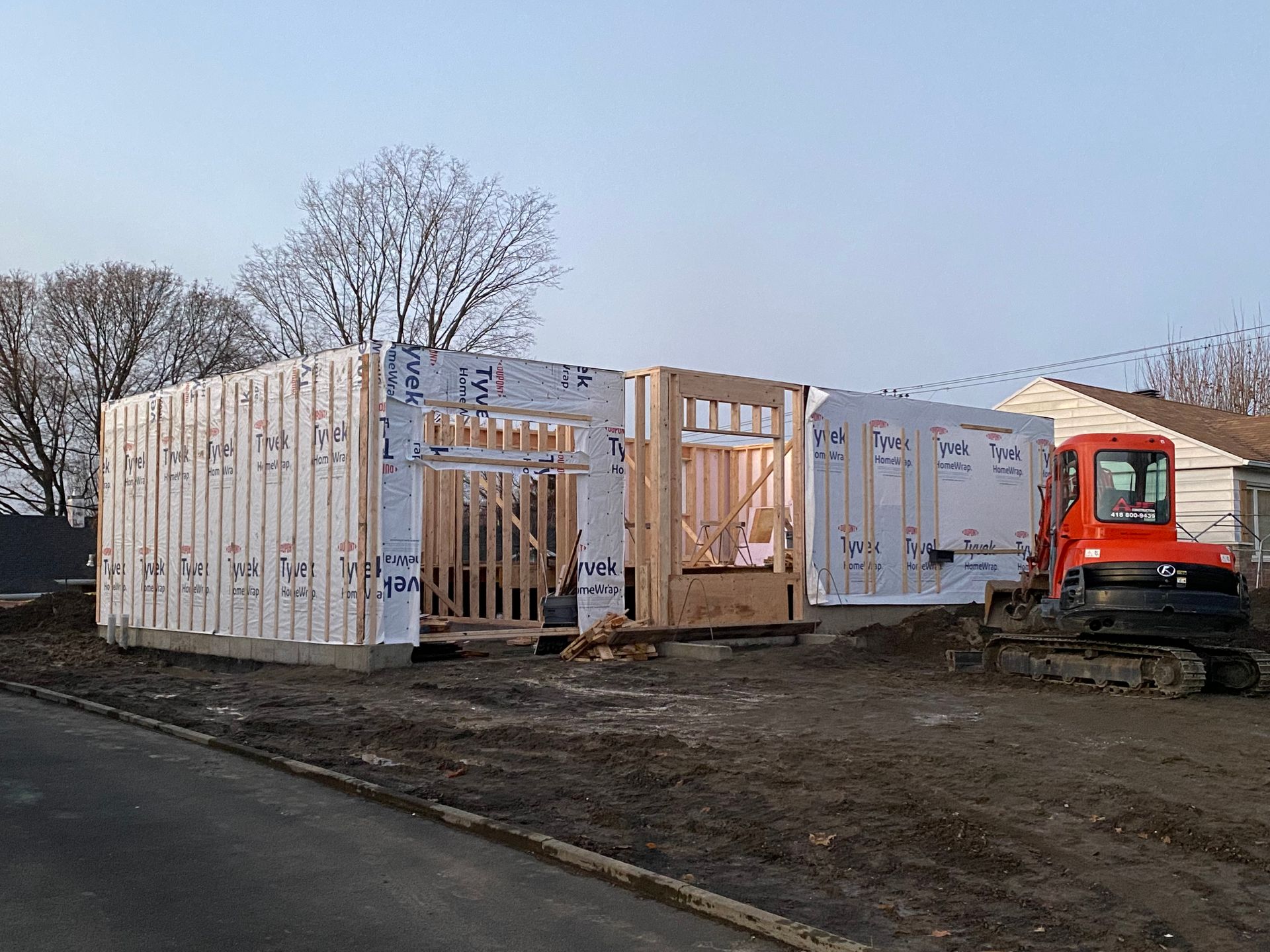 Une maison est en construction avec un bulldozer au premier plan.