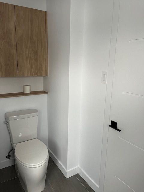 Une toilette est située dans une salle de bain à côté d'une porte.