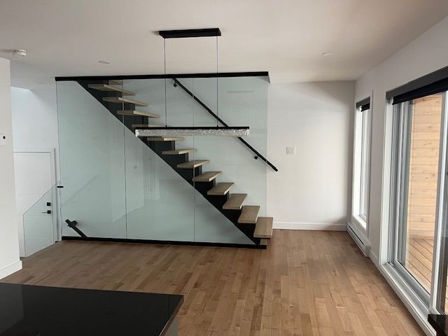 Une pièce vide avec un escalier et une rampe en verre