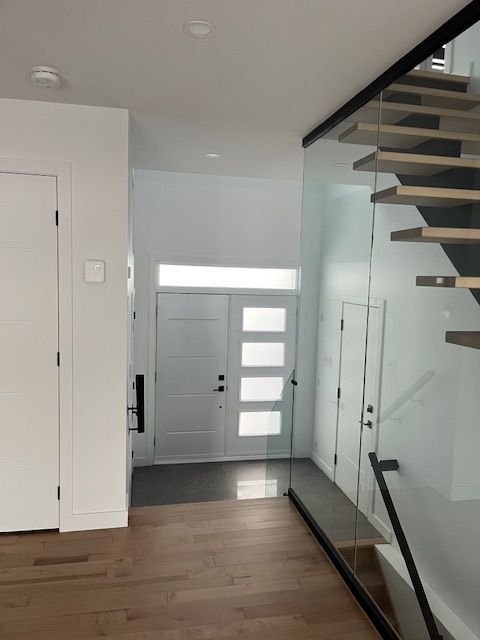 Un couloir avec un escalier en verre et une porte blanche