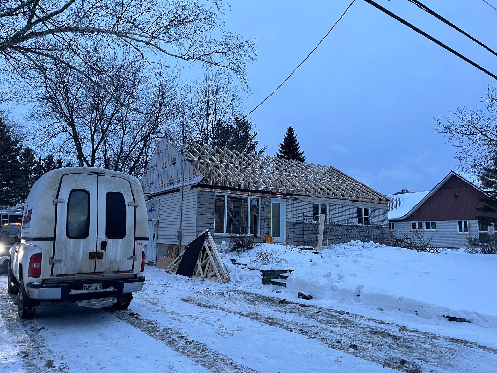 Une camionnette blanche est garée devant une maison en construction