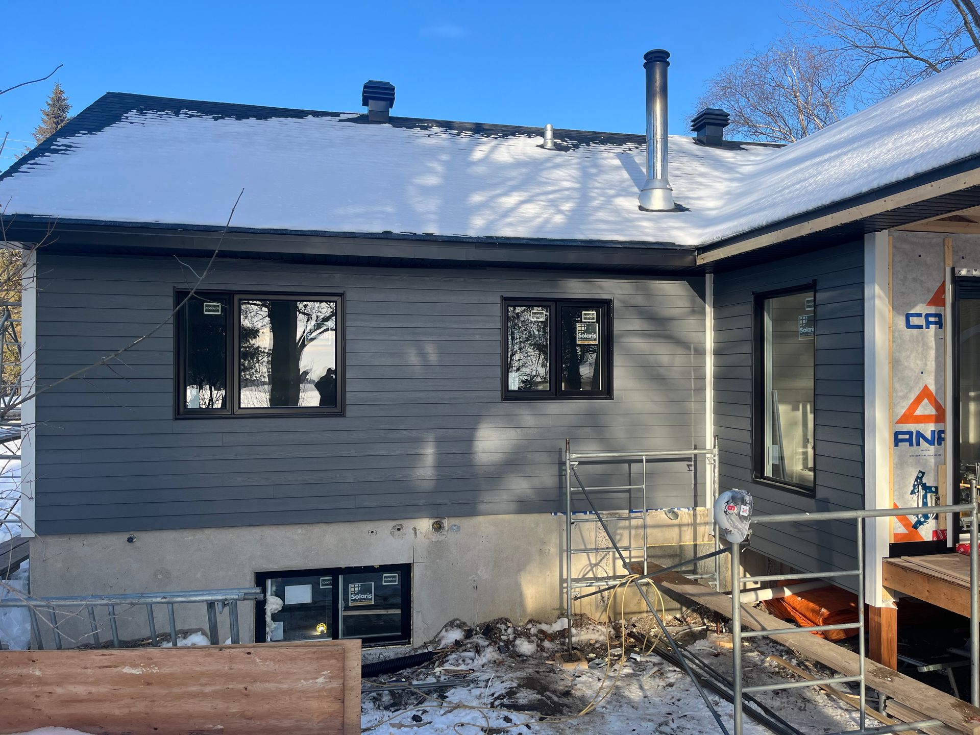Une maison est en cours de rénovation en hiver avec de la neige sur le toit.