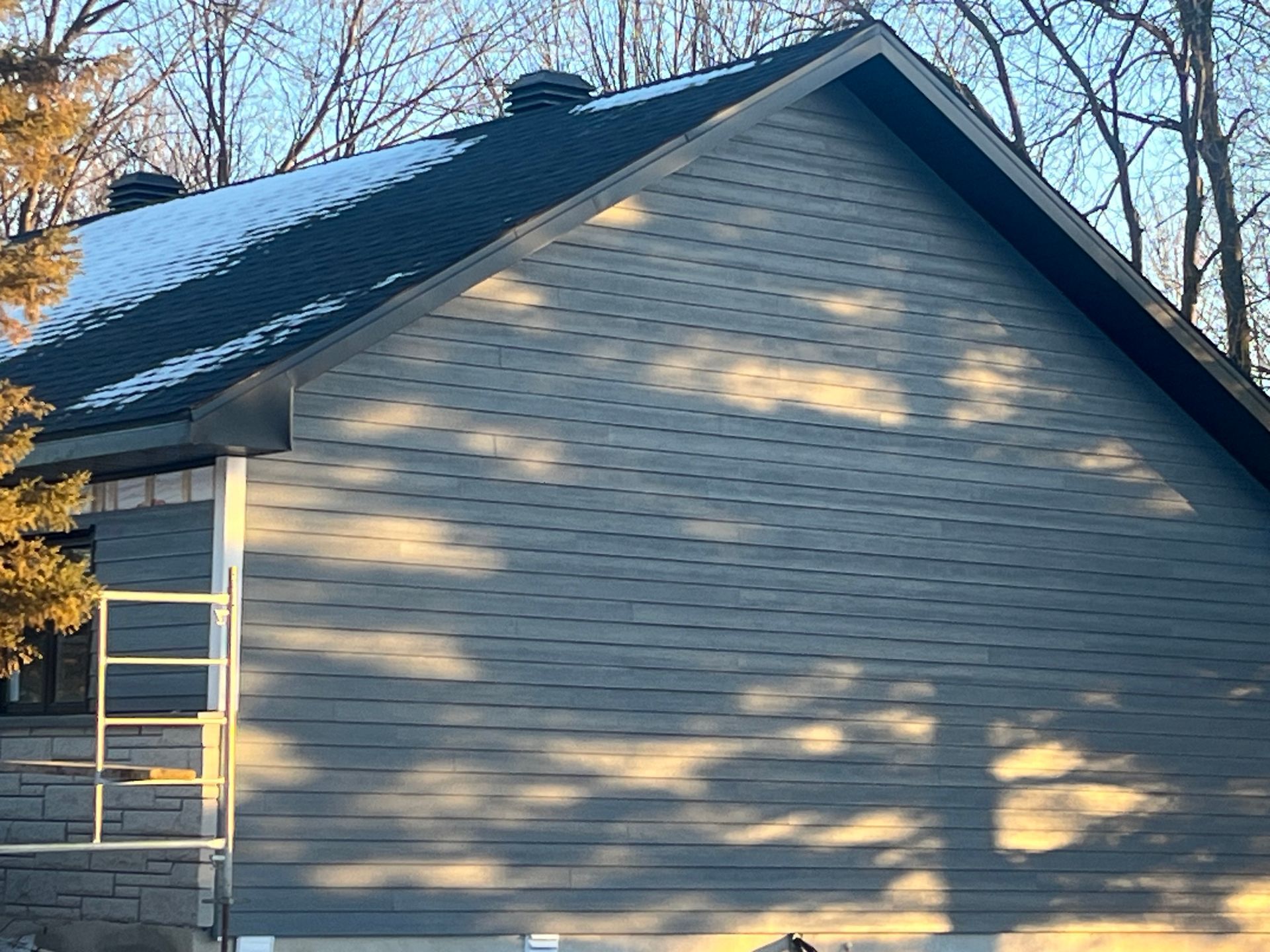 Une maison avec un toit noir et une échelle sur le côté.