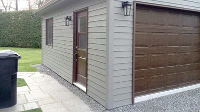 Un garage avec une porte et une fenêtre à côté d'une poubelle.