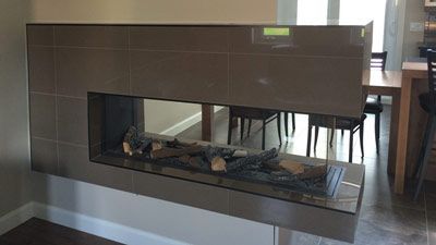 Une cheminée dans un salon avec une salle à manger en arrière-plan.