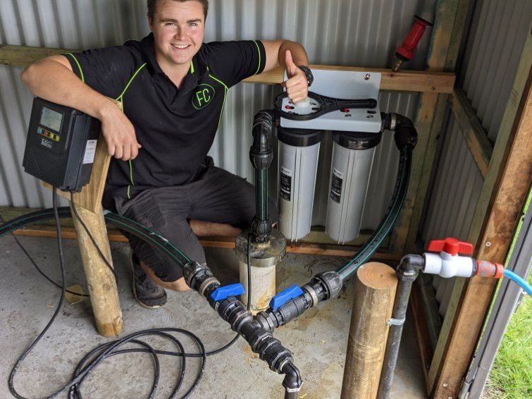 A Man is Sitting Next to a Water Pump and Giving a Thumbs Up — FarmCare in Mullumbimby, NSW
