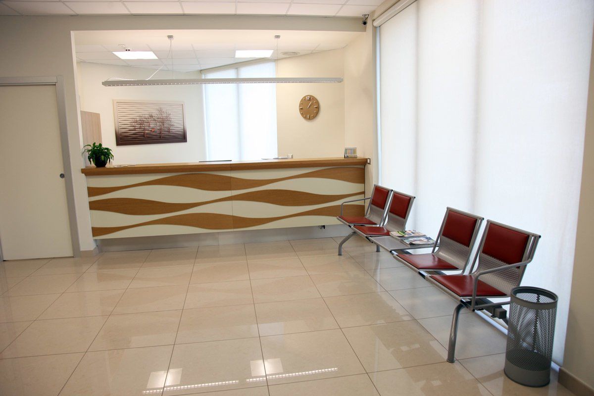 Una sala d'attesa con sedie e un bancone in un ospedale.