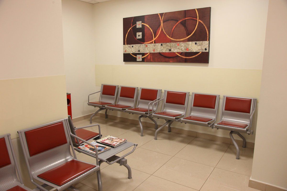 Una sala d'attesa con sedie rosse e un dipinto sul muro