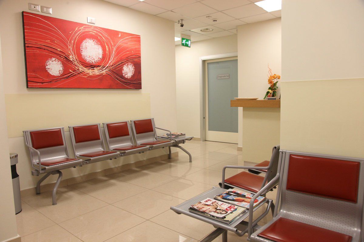 Una sala d'attesa con un tavolo, delle sedie e un quadro alla parete.