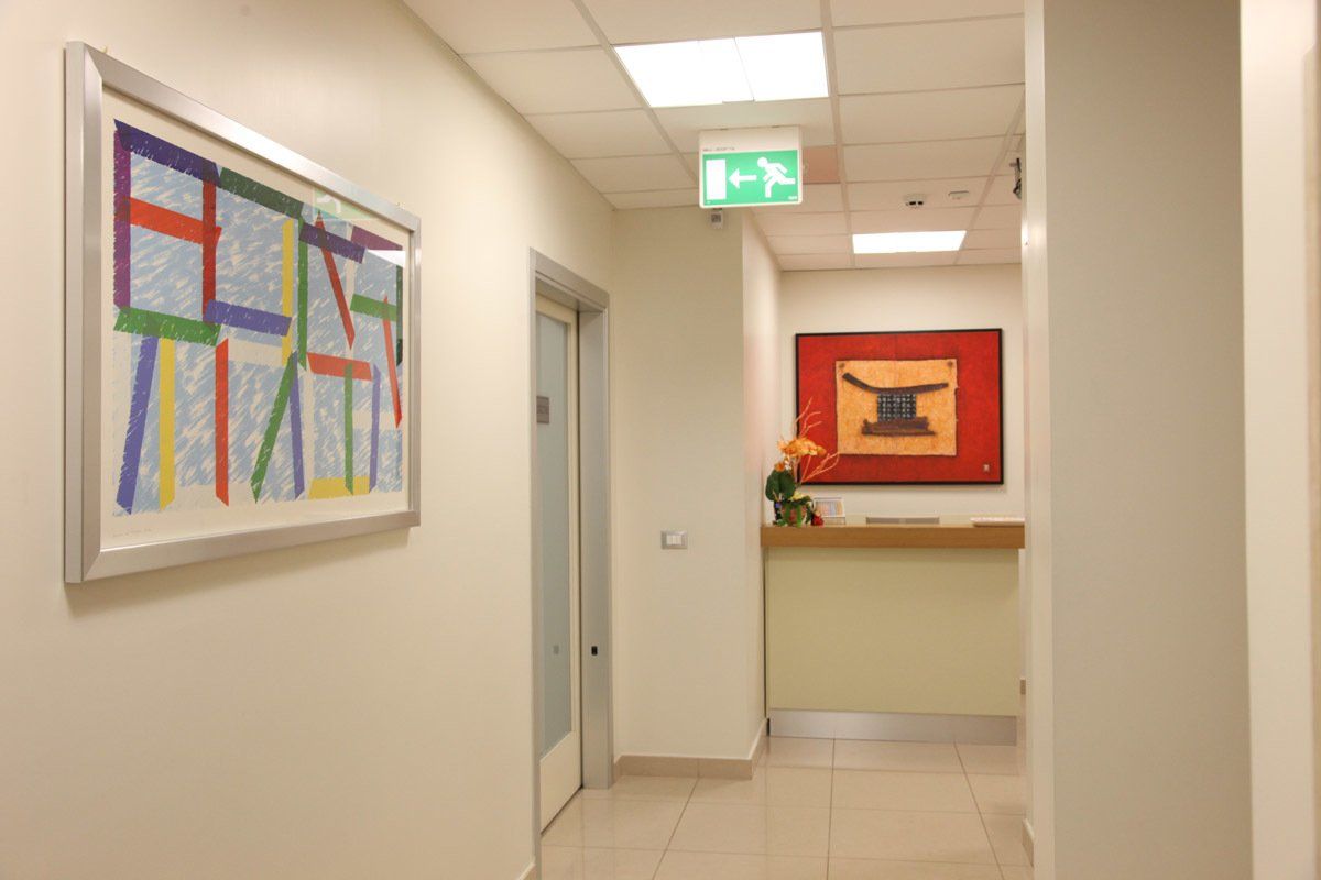 Un corridoio con un dipinto sul muro e un cartello di uscita verde