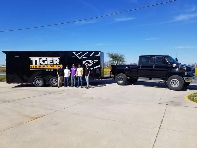A group of people are standing in front of a tiger trailer and truck.