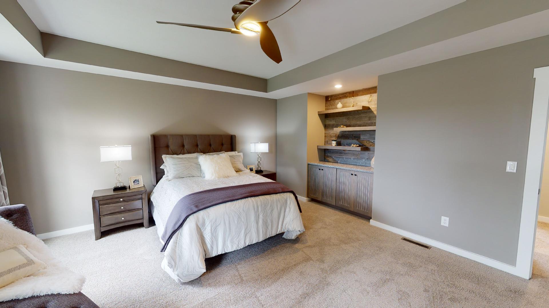 primary bedroom with recessed ceiling and built-in shelves
