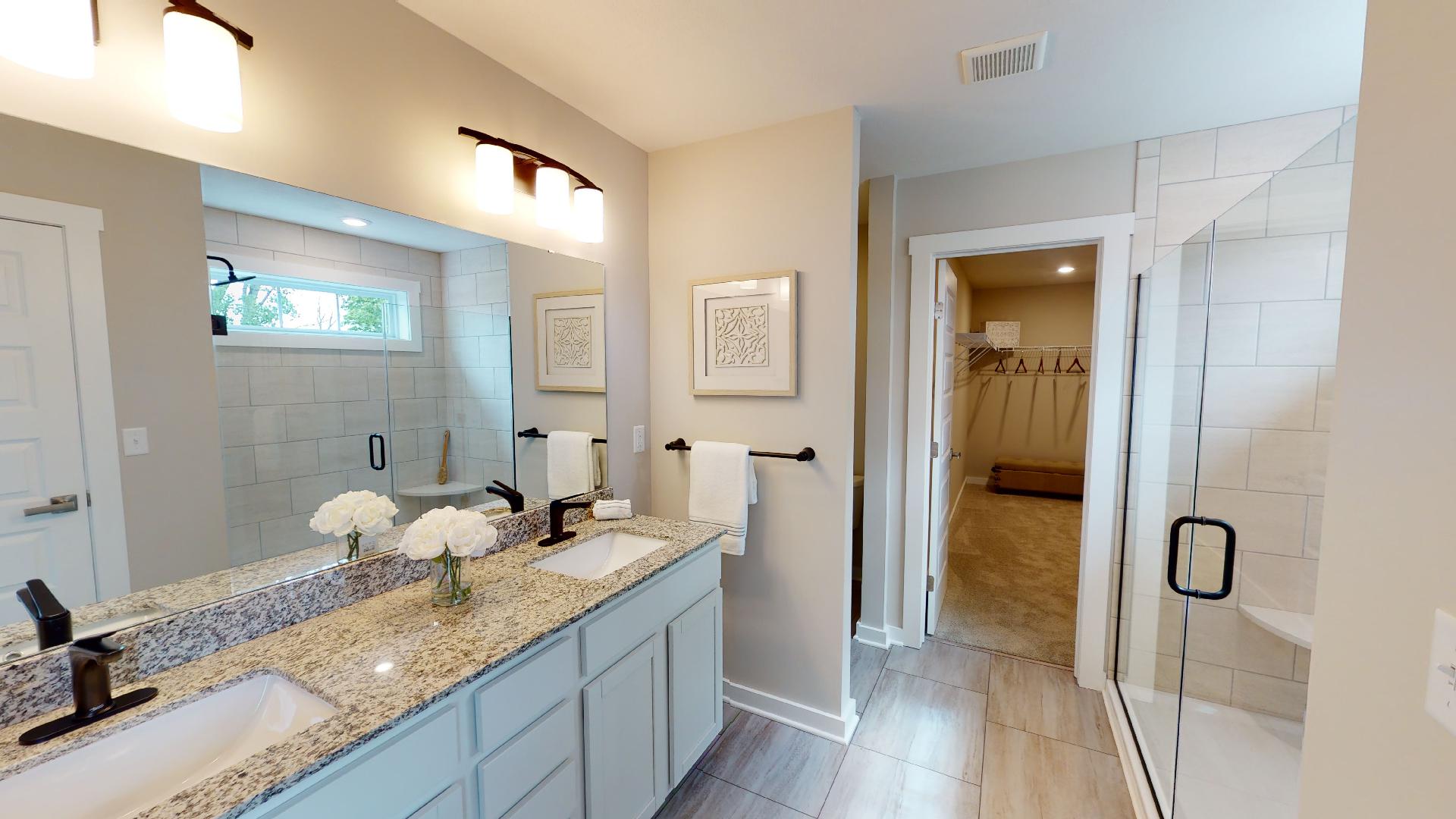 primary bathroom with double vanity and walk-in closet