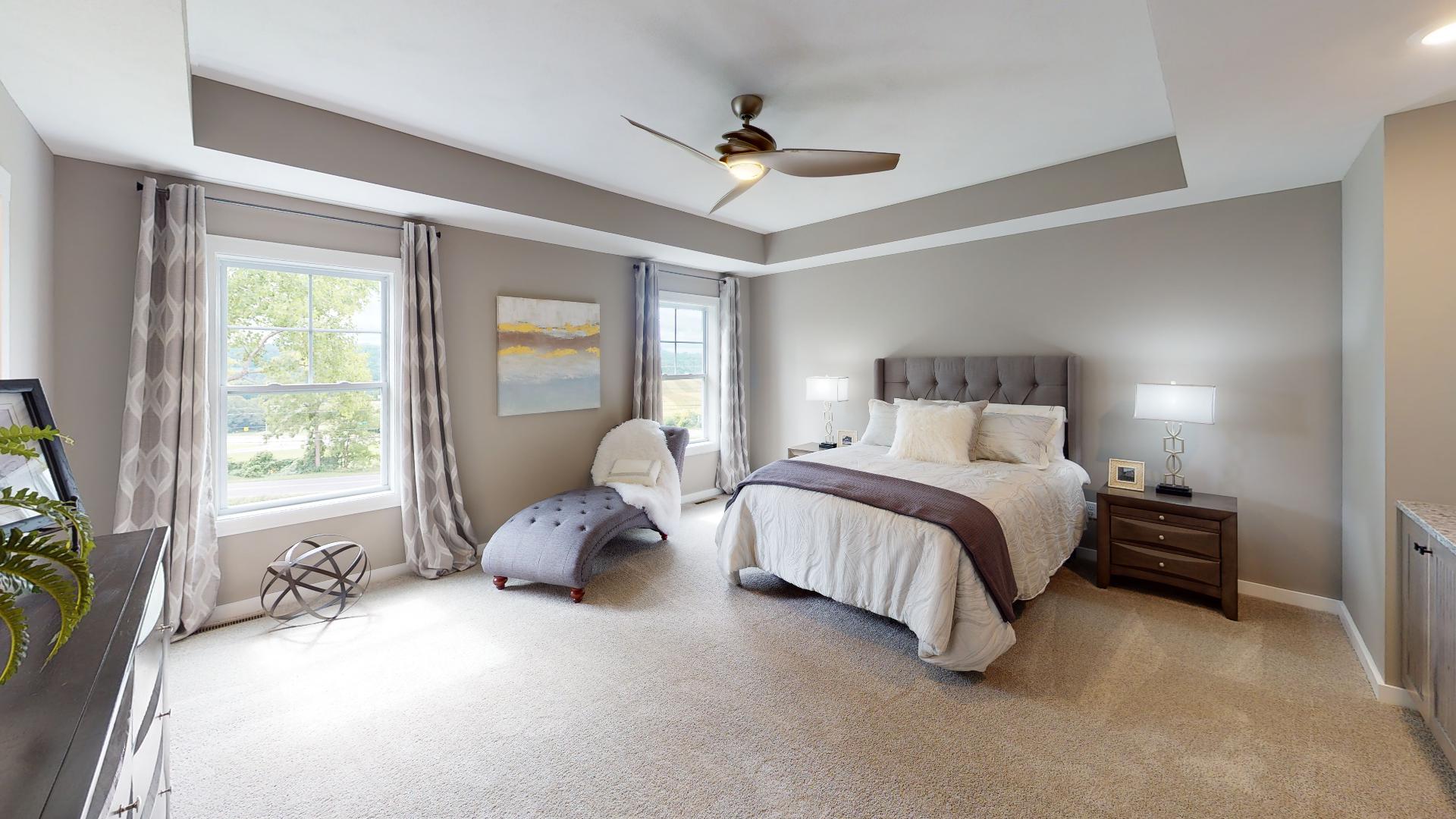 primary bedroom with recessed ceiling and ceiling fan