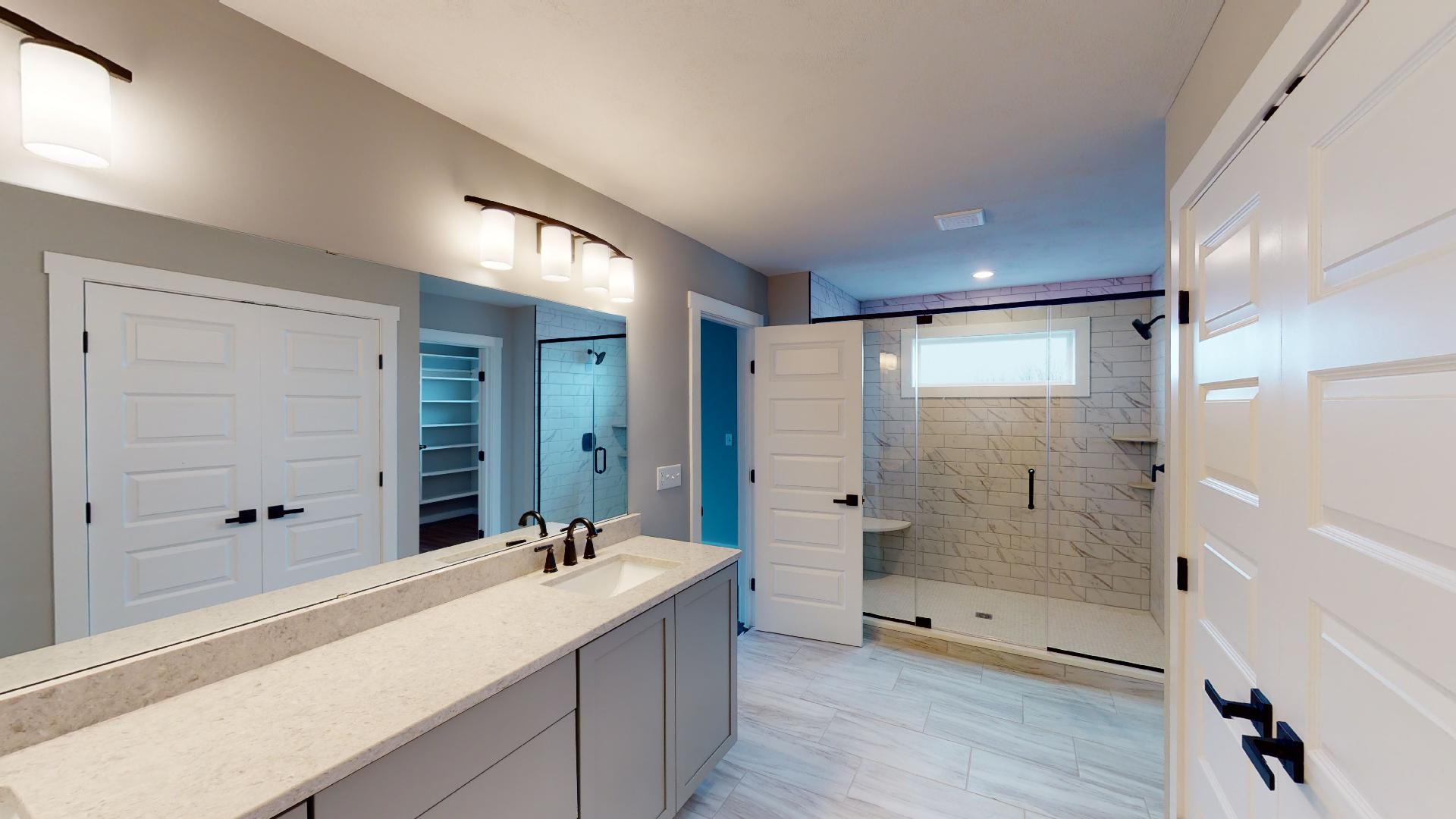 primary bathroom with shower, double vanity and French door closet