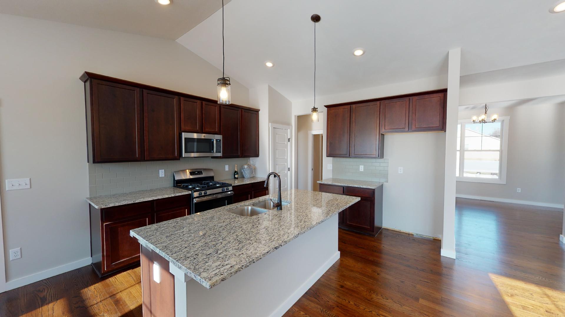 kitchen with vaulted ceiling and dinning room in background