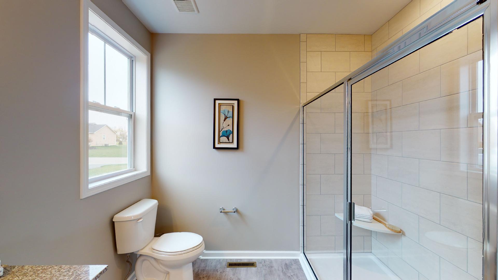 toilet across from tile shower with glass door