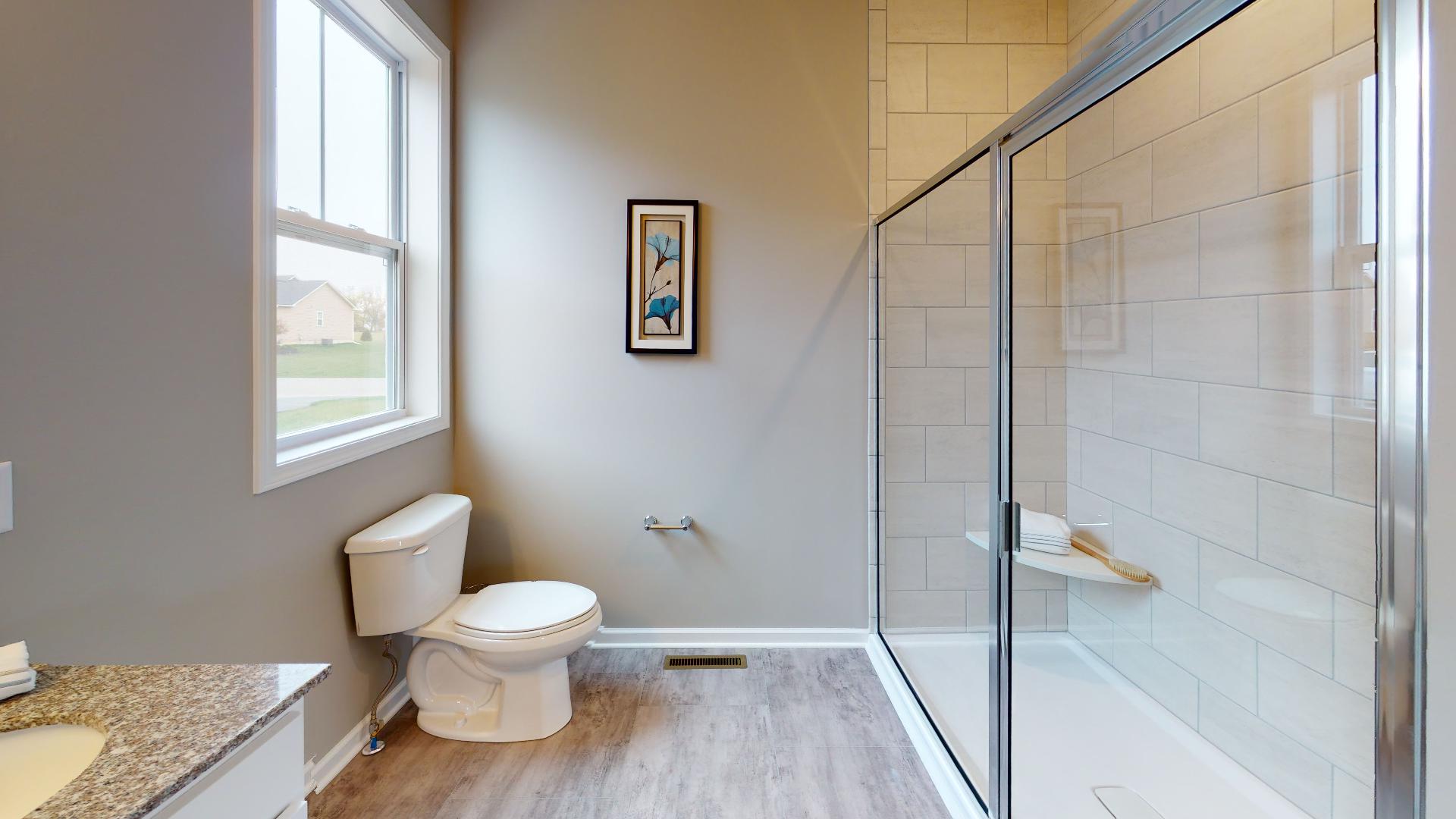 toilet across from tile shower with glass door