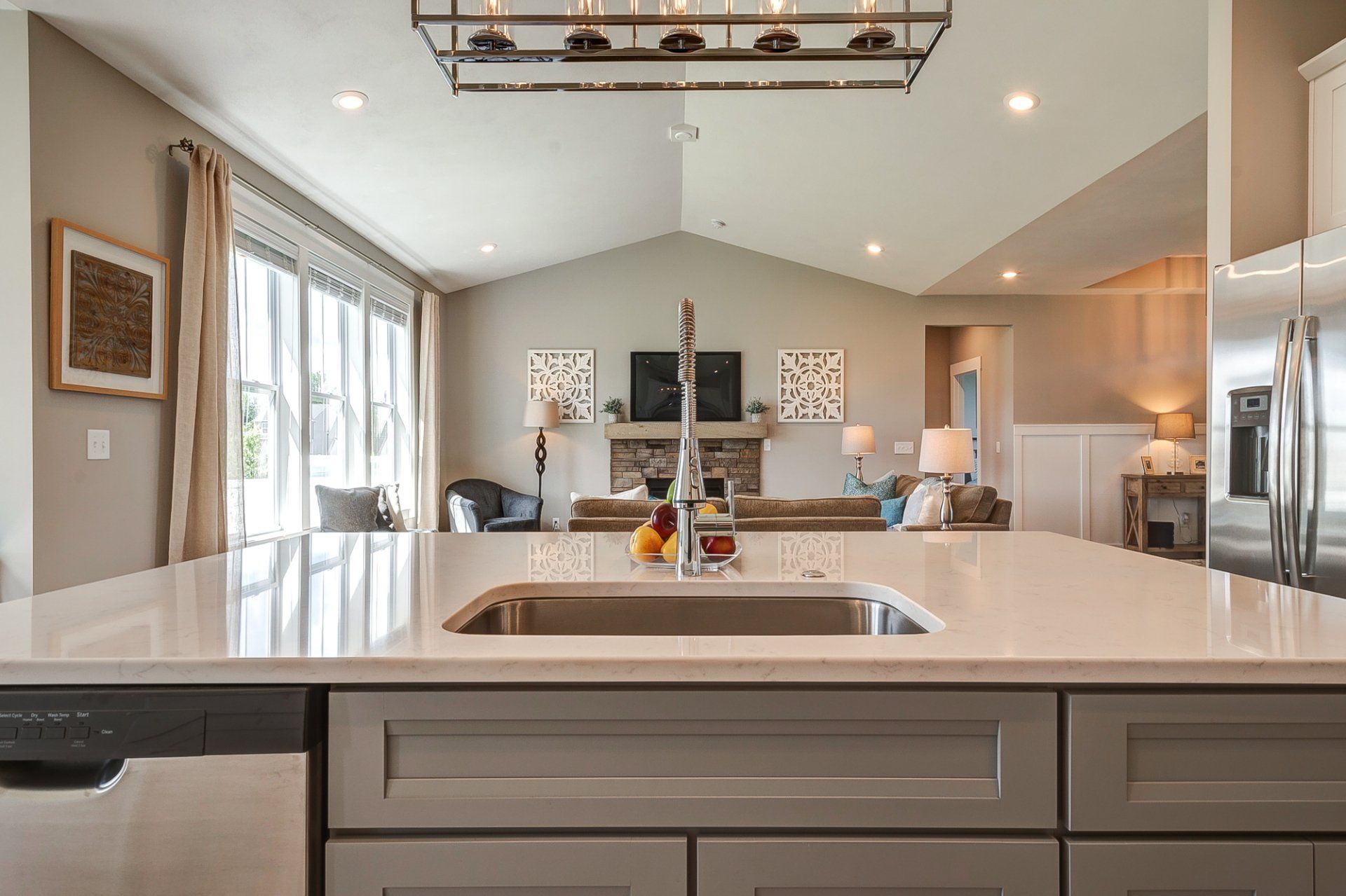 kitchen island with sink and dishwasher looking out into living room