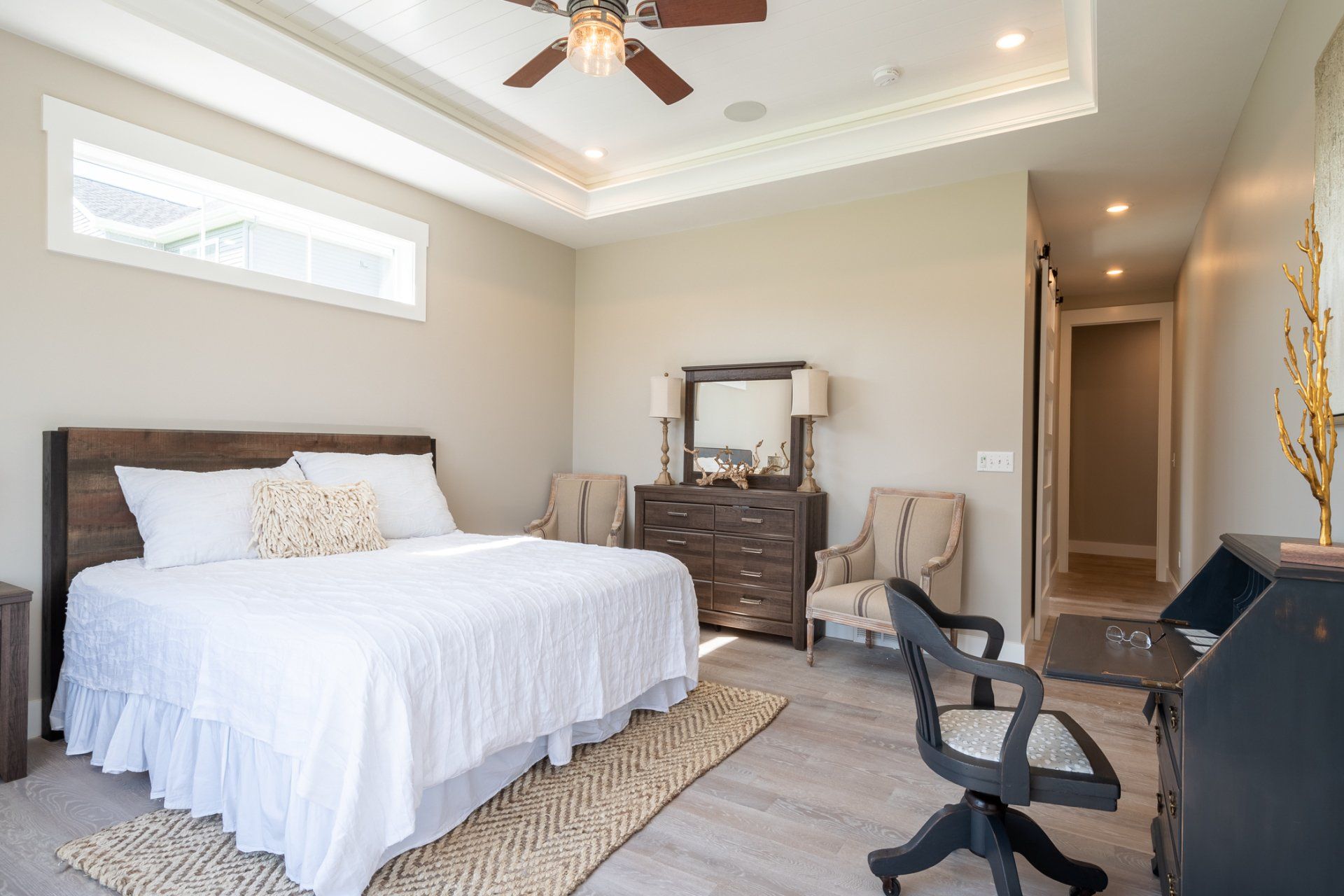 primary bedroom with recessed ceiling and ceiling fan