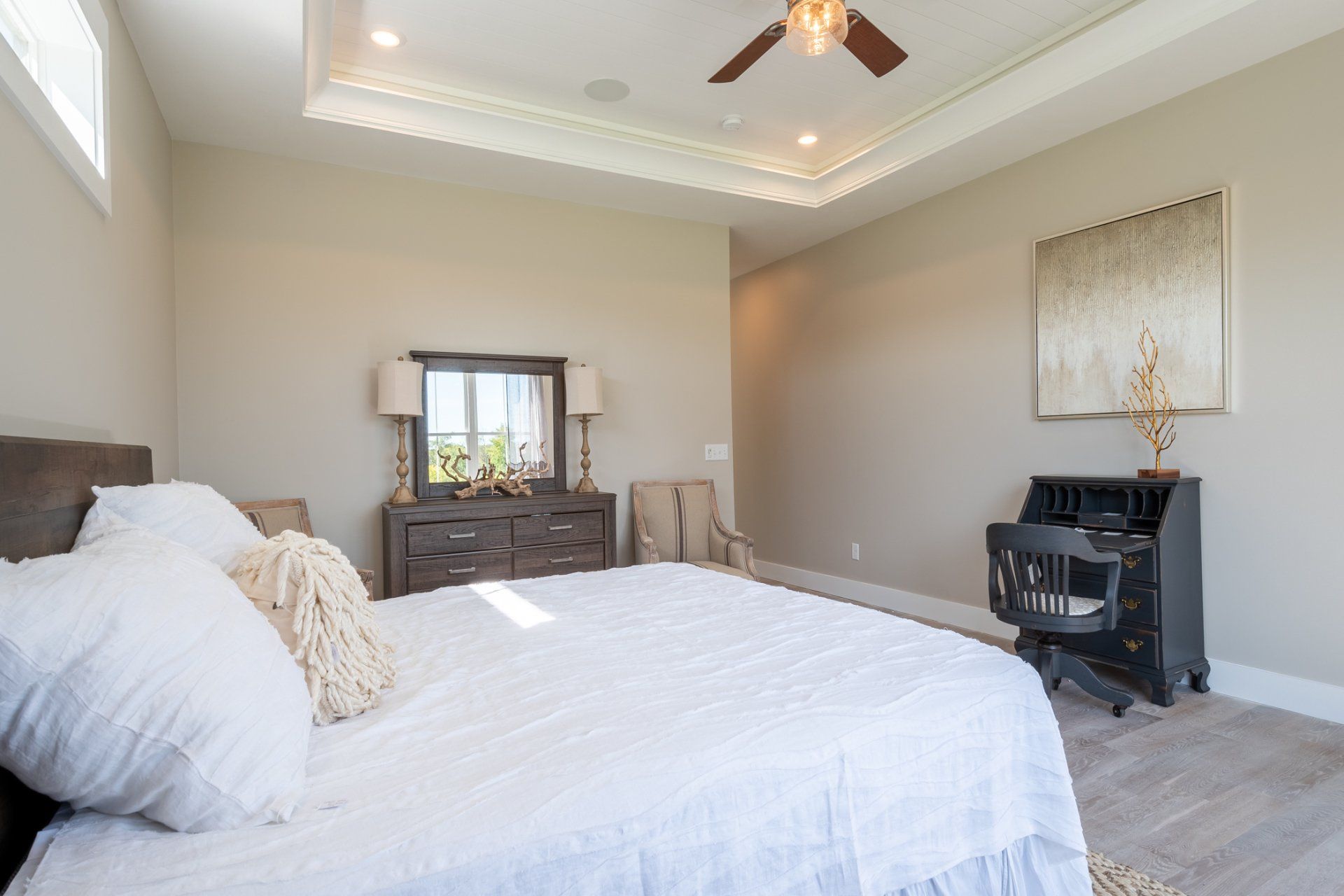 primary bedroom with recessed ceiling and ceiling fan