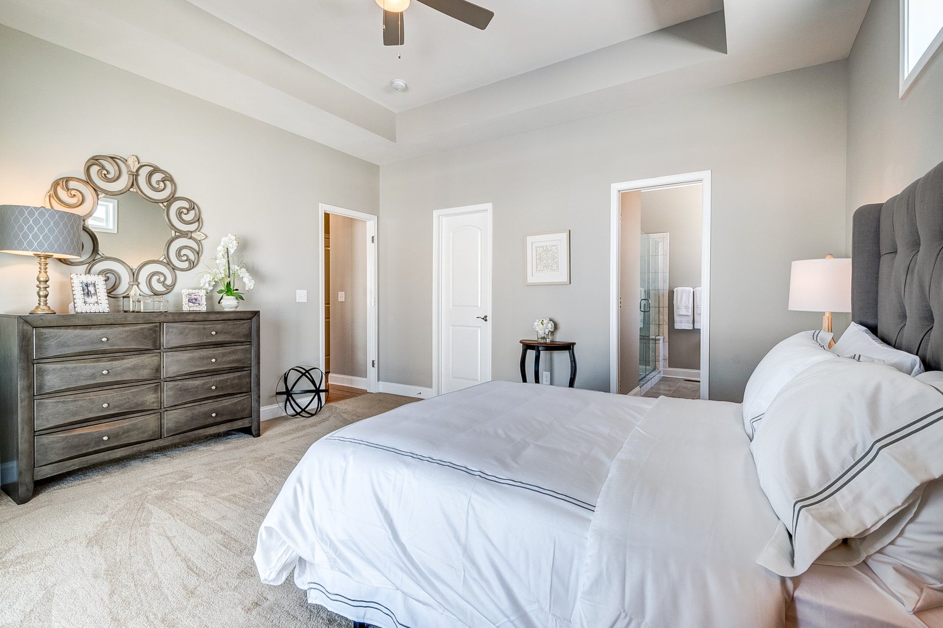 primary bedroom with recessed ceiling and ceiling fan