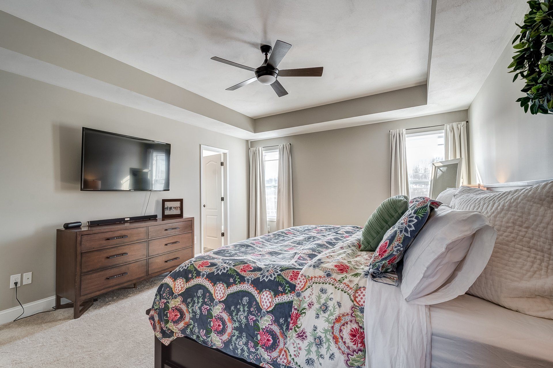 primary bedroom with recessed ceilings and ceiling fan