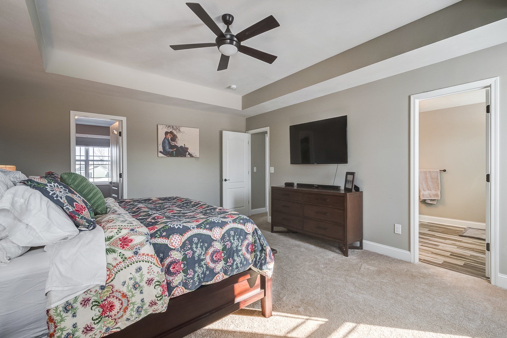 primary bedroom with recessed ceilings and ceiling fan
