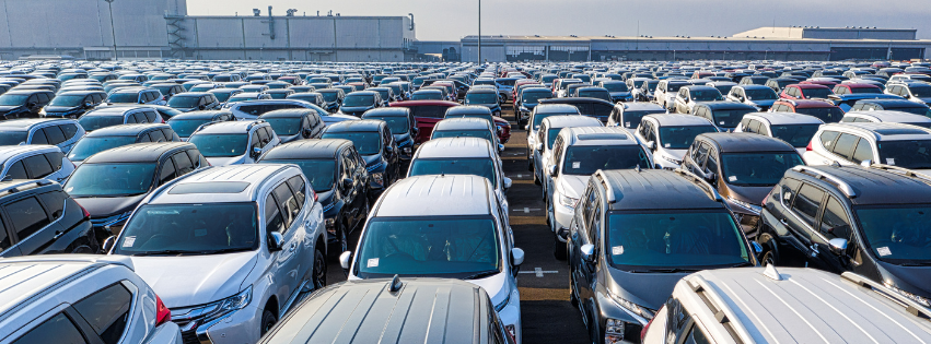 A large parking lot filled with rows of parked cars, showcasing various models and colors 