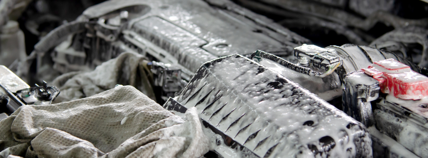 The image shows the engine compartment of a car covered in foam, possibly from a cleaning process.
