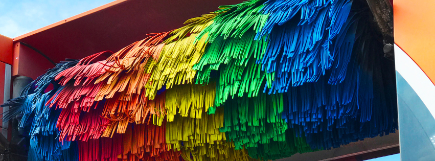 Close-up view of colorful car wash brushes arranged in rainbow hues