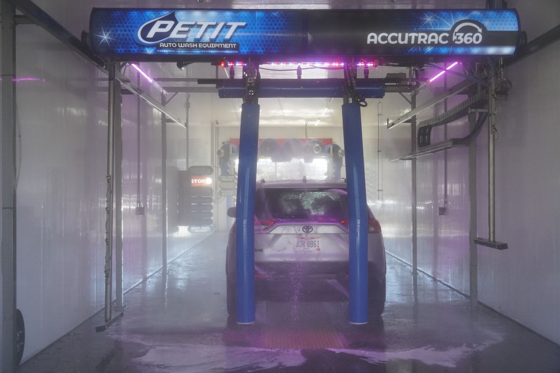 Automatic car wash spraying soap and water onto a black pickup truck.