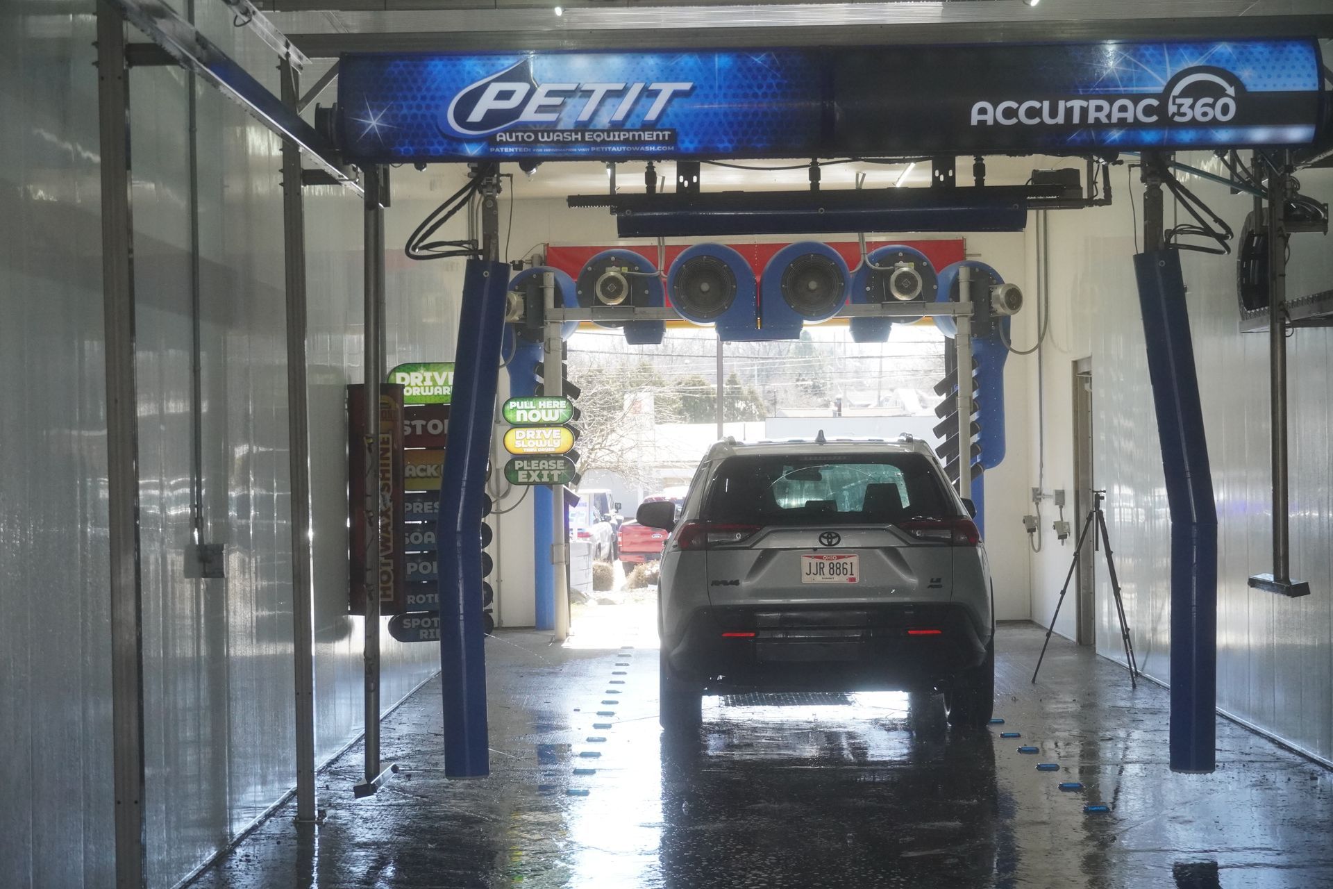 Vehicle under high-pressure water jets inside a drive-through car wash tunnel.
