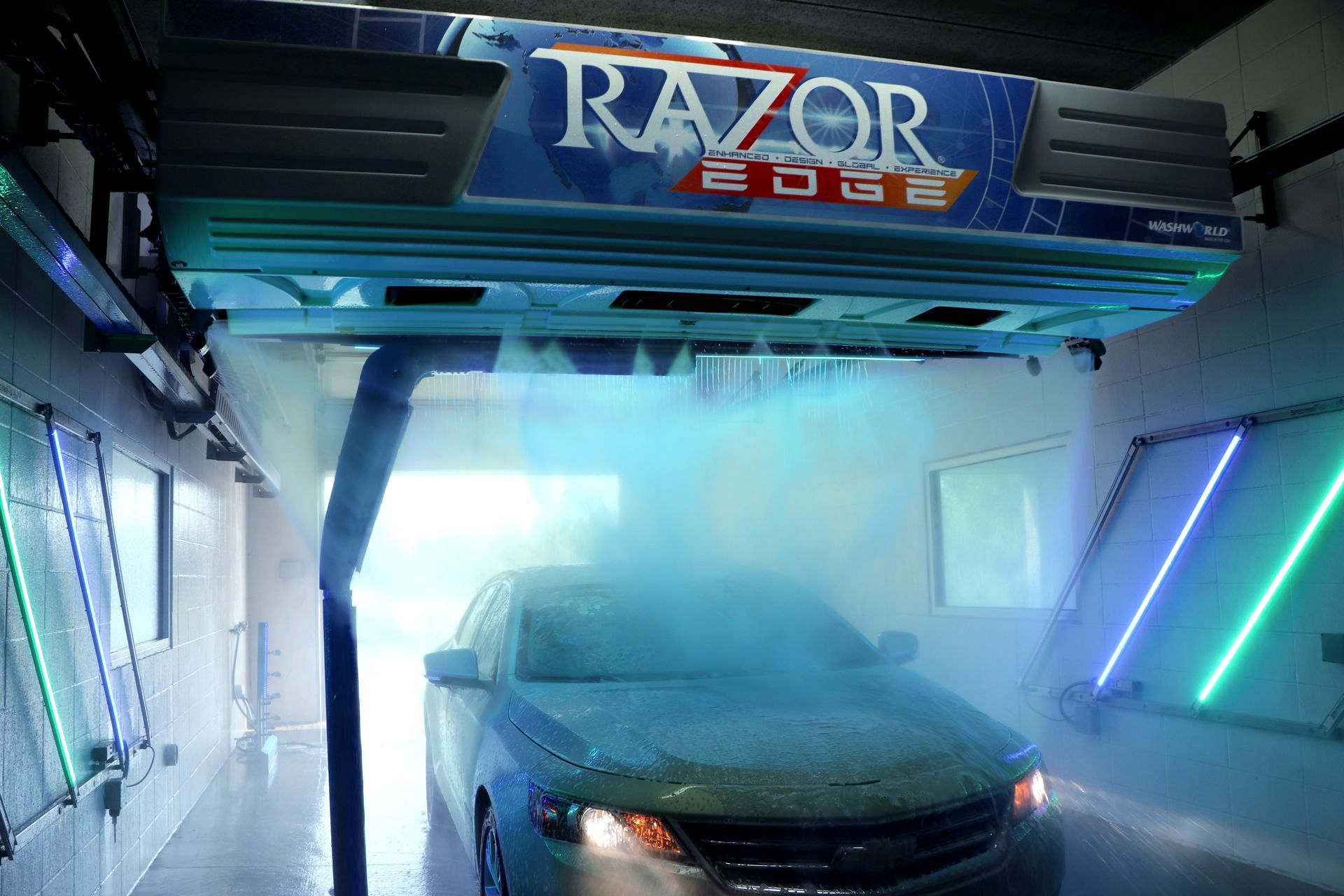 Car undergoing wash inside an automated Razor Edge car wash system with blue spray.