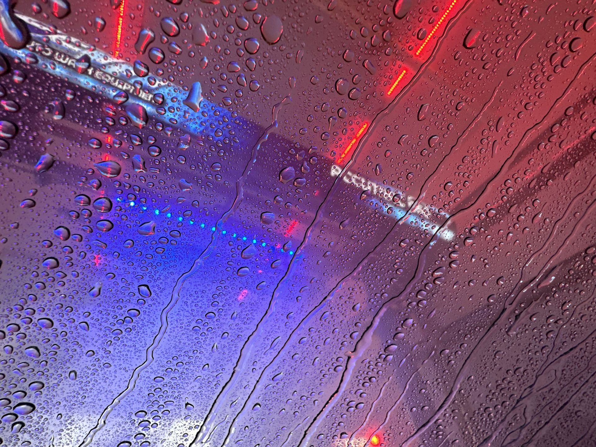 Vehicle side view covered in foam as high-pressure jets rinse it clean.