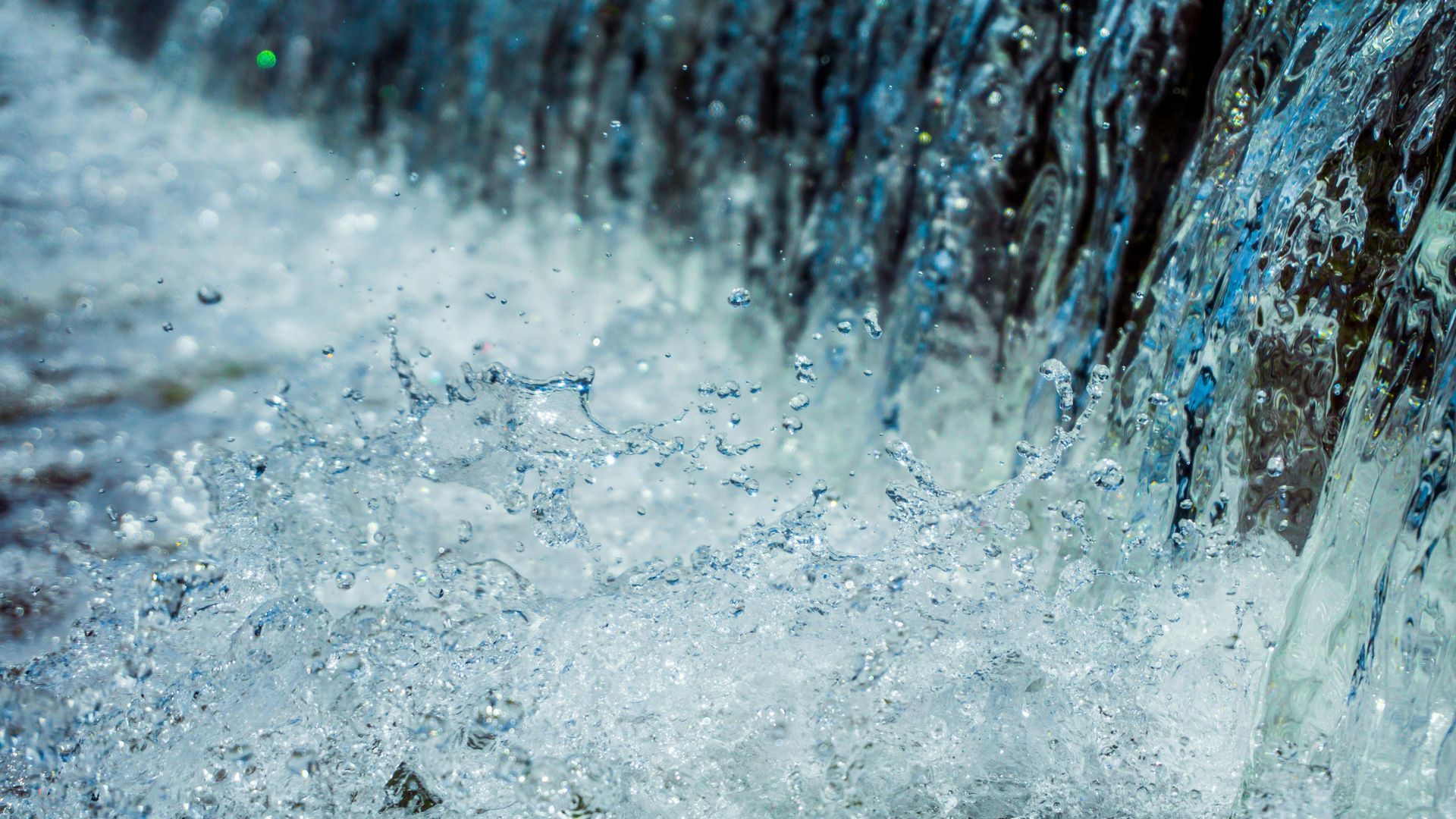 The image shows a close-up of water splashing, with droplets scattering in the air.