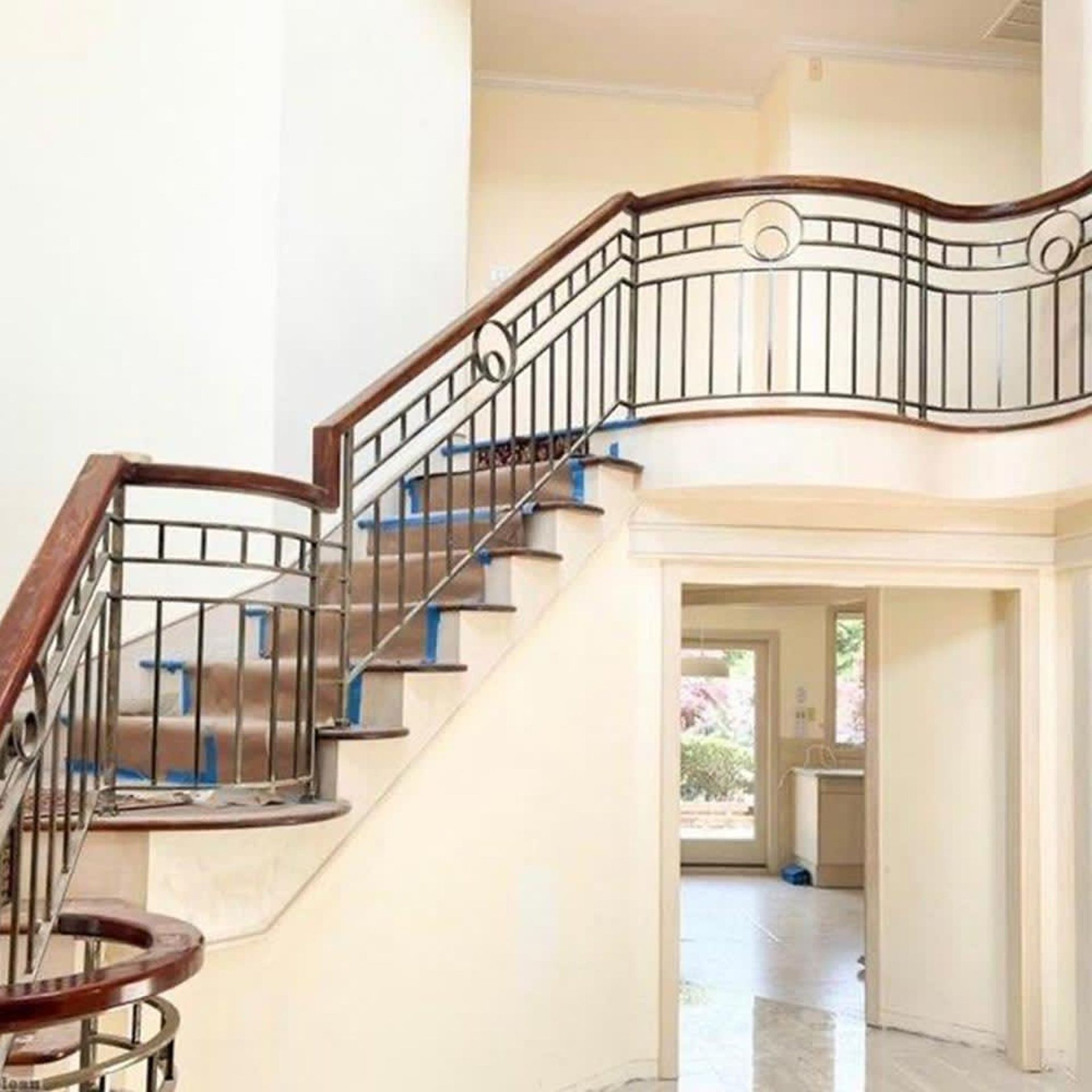 Curved indoor staircase with dark railing and wooden handrail in a bright home interior.