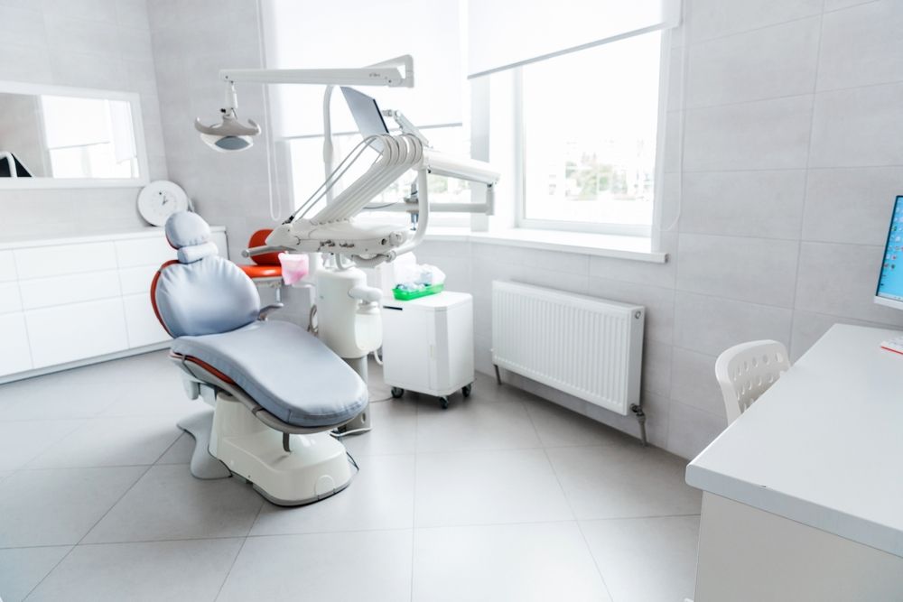 Dental clinic chair with overhead exam light in a bright, modern treatment room