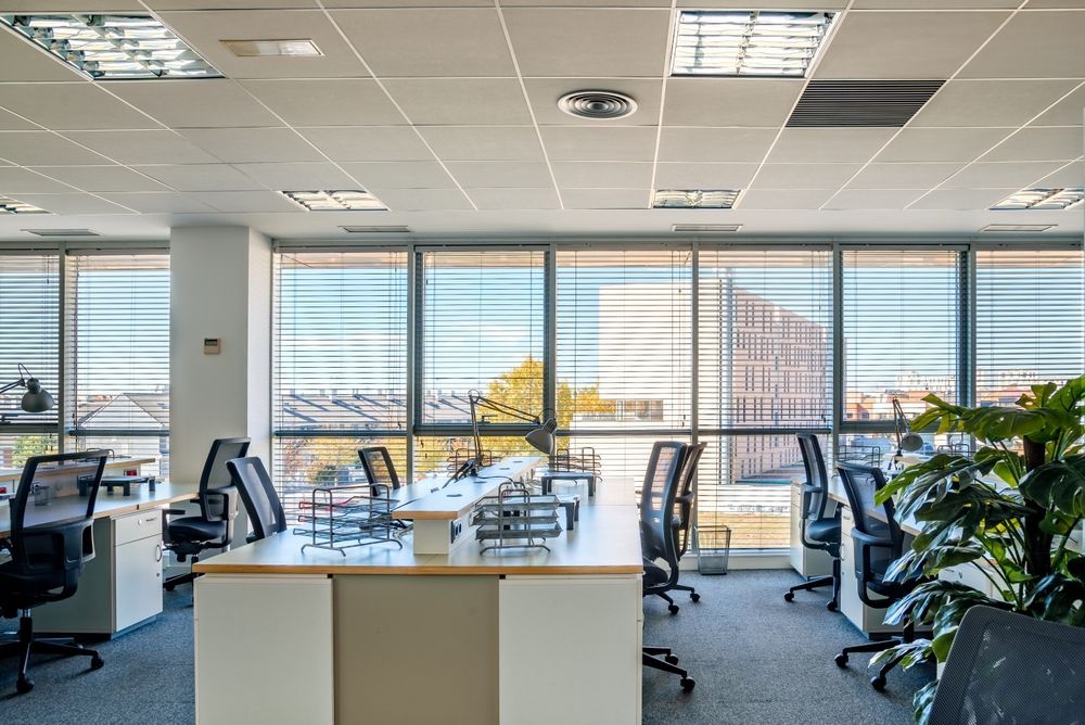 Bright modern office with desks, computers, chairs, large windows, and city view
