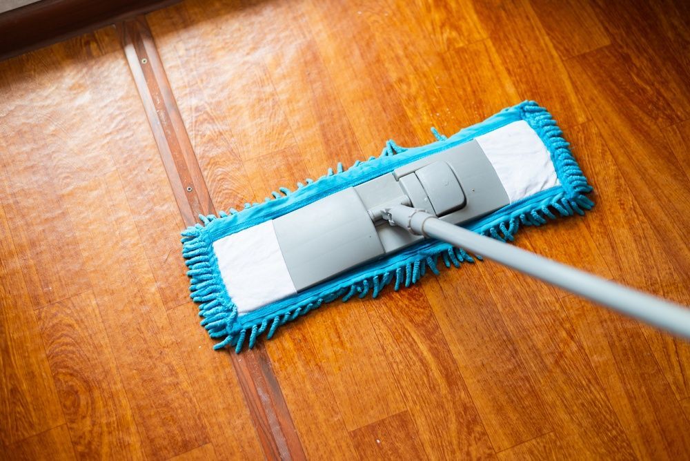 Blue mop cleaning a wooden floor with a silver handle