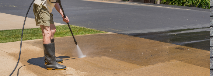 A person wearing shorts and boots power washing a concrete surface on a sunny day.